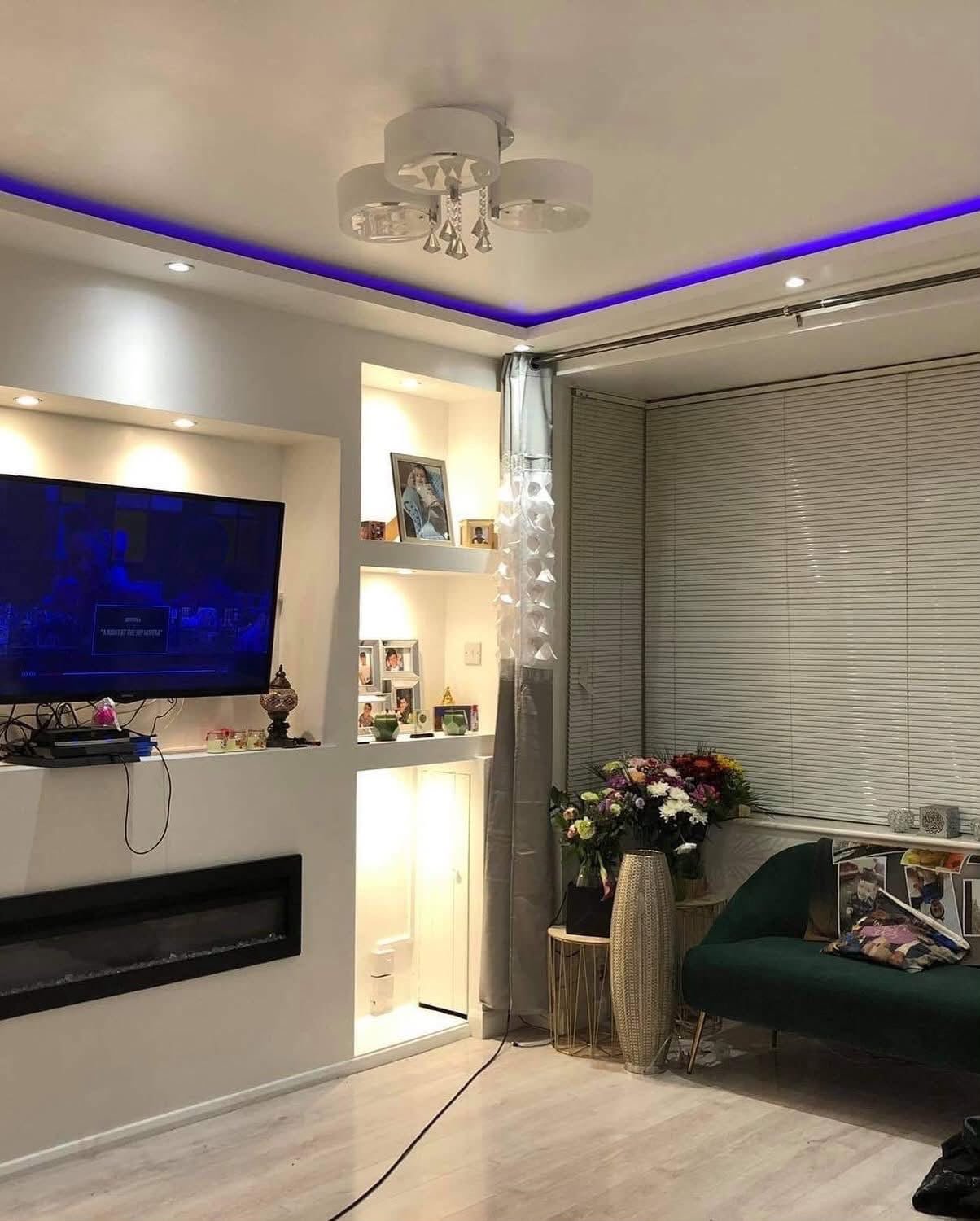 Decorated living room with lit alcove shelving and LED coving